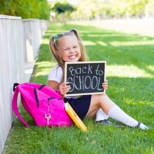 a child holding on a blackboard saying "back to school"